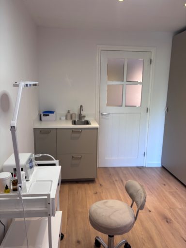Voorbereidingsruimte met wastafel, opbergkast en verstelbare pedicurelamp voor een hygiënische voetbehandeling